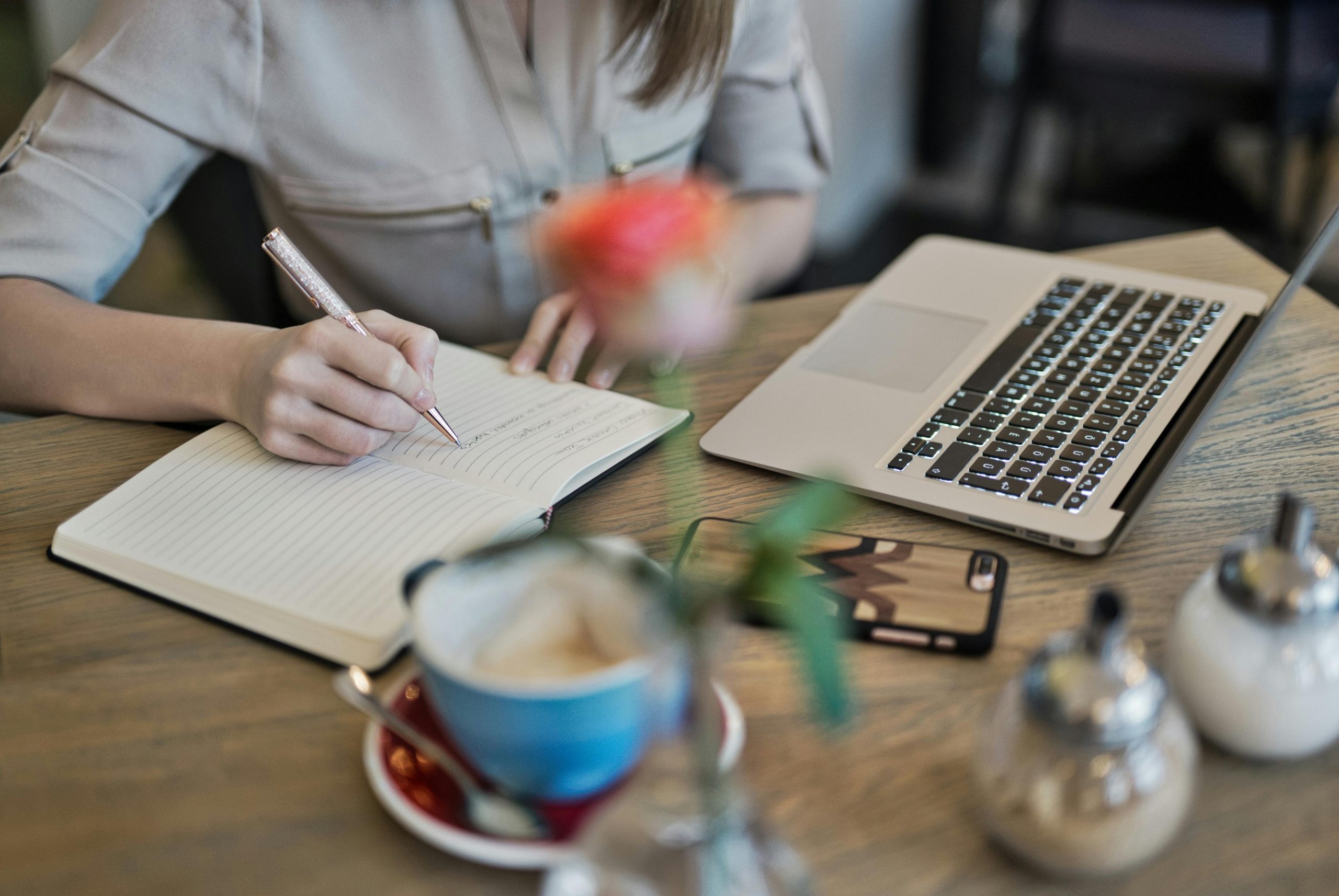 An employee taking notes for a content marketing strategy while working on a laptop
